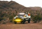 Rugged Toyota Tacoma overlanding truck with bright lights in desert mountains. Explore with this unique RV rental!