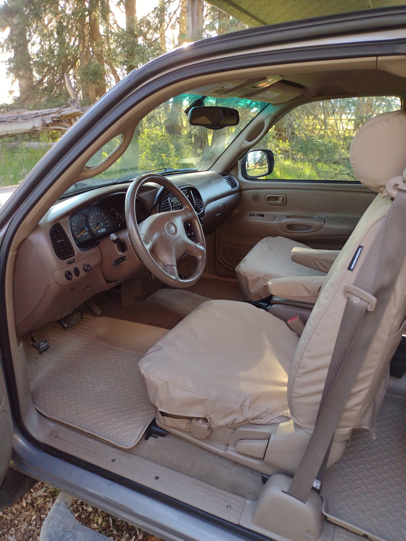 Detailed tan vehicle interior: dash, steering wheel, and seats with Covercraft covers. Perfect for any rv rental trip.
