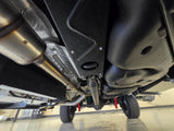 Looking up at the undercarriage of an RV rental, featuring a robust exhaust system, fuel tank, and off-road suspension.