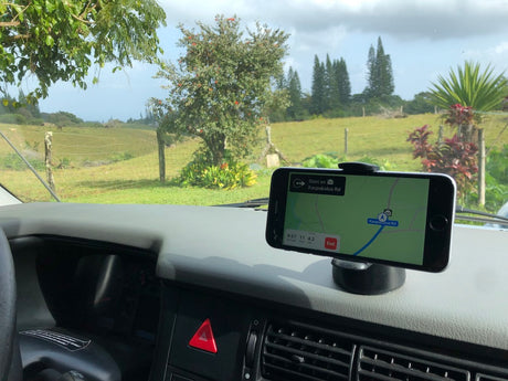 RV rental journey: Phone navigation on dashboard shows Kaupakalua Rd with scenic green fields and trees outside.