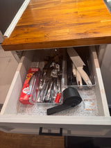 Organized kitchen drawer in an RV rental, showing silverware, Cuisinart knives, storage bags, and a collapsible measuring set.