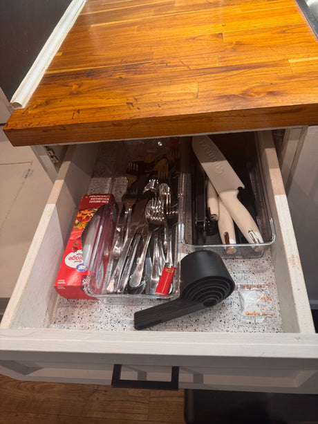 Organized kitchen drawer in an RV rental, showing silverware, Cuisinart knives, storage bags, and a collapsible measuring set.