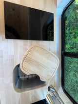 RV rental kitchenette: induction cooktop, sink with cutting board, and green window view.