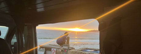 Scenic Carmel Beach sunset from an RV rental, capturing ocean views & a person by signs.
