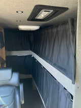 RV rental interior setup with dark privacy curtains for bunk beds, overhead lights, and a comfortable seat.