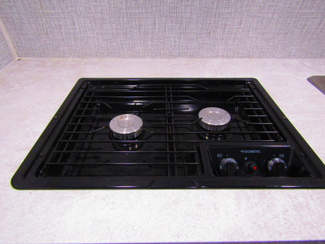 A Dometic two-burner stovetop, integrated into a light countertop, is ready for cooking in this RV rental kitchen.