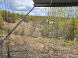 Scenic spring view from an RV rental. Through screen, green trees, melting snow, and cloudy sky are visible.