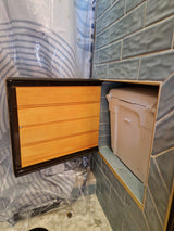 RV rental shower: clever access panel opens to reveal a built-in storage bin within tiled walls.