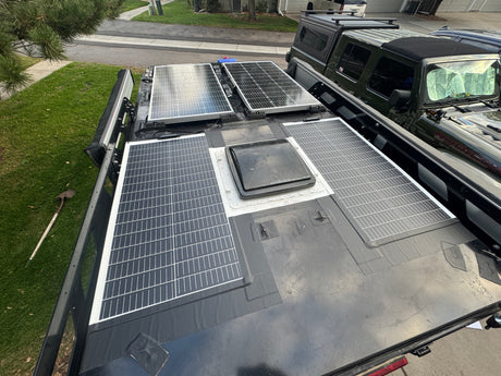 Overhead view of an overland vehicle's roof, featuring multiple solar panels & a vent. Great for an rv rental or adventure trip.