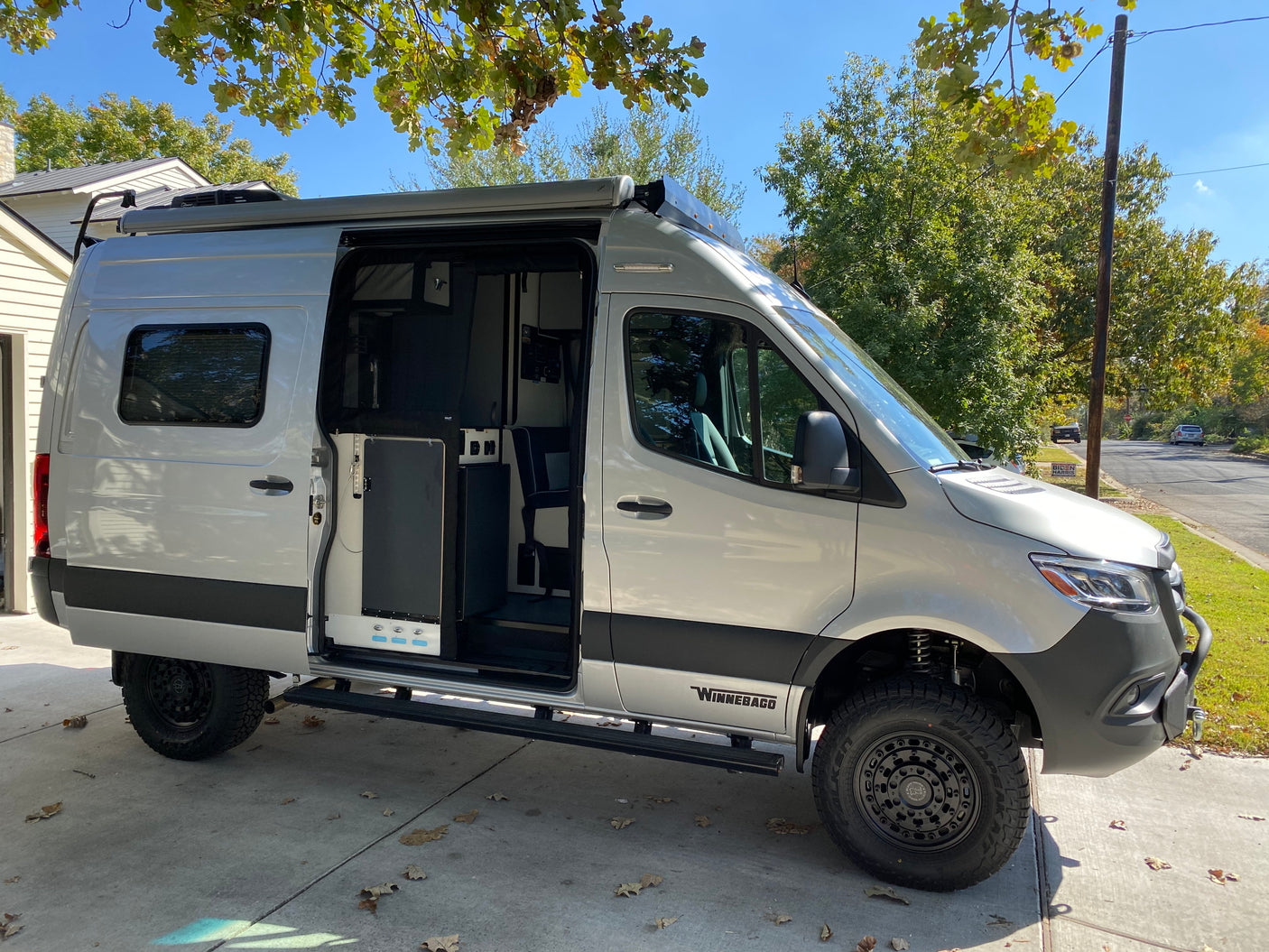 Stylish silver Winnebago camper van for RV rental, parked with open side door showing interior, ready for adventures.