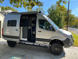 Stylish silver Winnebago camper van for RV rental, parked with open side door showing interior, ready for adventures.