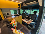 Explore this RV rental's versatile interior: a bright kitchenette, cozy seating, & mobile desk with laptop. Perfect for van life adventures.