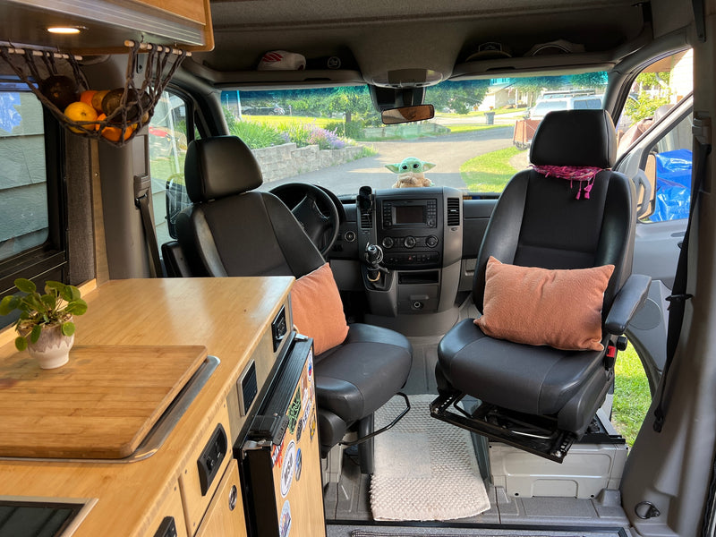 Cozy RV rental interior with custom wood kitchenette, rotating seats, and playful decor like Baby Yoda. Perfect for van life adventures! — photo 16