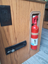 RV rental interior featuring a power outlet, Sony stereo, and an essential fire extinguisher mounted on wood paneling.