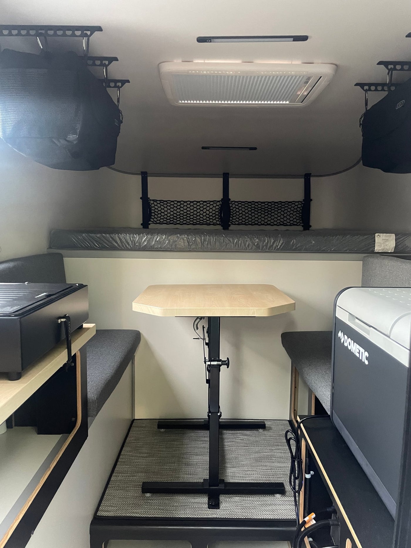  with our "Scout" truck camper rv rental in the background.|Inside a compact RV rental. Features a bed — photo 8