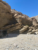 Off-roading in a rugged desert canyon with layered rock walls, a Jeep, and explorers. Imagine this adventure with an RV rental!