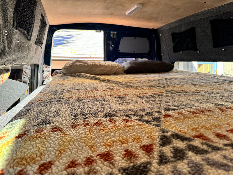  custom cupholders & autumn views. Great for road trips!|Custom dark blue RV rental van's rear view. Open doors reveal a cozy raised bed — photo 14