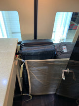 RV rental interior storage: Large luggage & a bag are secured in the back by a mesh net, ready for travel.