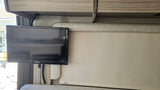 RV rental interior: A Jensen TV is mounted next to a window, below overhead cabinets and above an MCD roller shade.