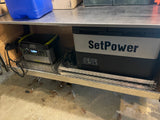 This RV rental setup features a portable fridge/freezer and a power station on a diamond plate shelf for off-grid use.