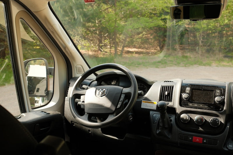  screened window with lush green forest views.|Cozy RV rental bed with striped bedding inside a pop-top camper. Ideal for comfortable rest on your travels.|Compact RV rental interior featuring a kitchen with stovetop — photo 10