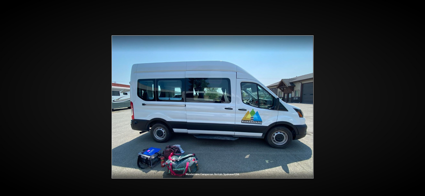 White Wandervans campervan with colorful bags, parked and ready for an RV rental. Perfect for your next travel adventure!