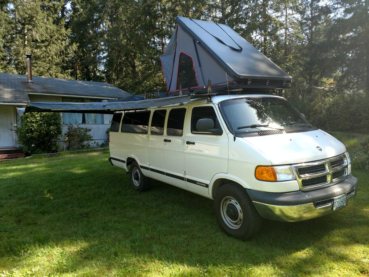  and paper towels for essential upkeep.|White camper van on a gravel lot with snow-capped mountains & forest in the background. An ideal RV rental for adventure.|White RV rental camper van parked on autumn leaves by trees — photo 4