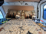A comfy RV rental bed with nature-themed bedding reading "Into the Forest I Go To Lose My Mind And Find My Soul." Ready for adventure!