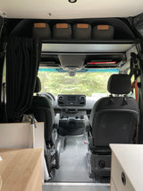 Interior of an rv rental camper van, showcasing the front cab, dashboard, seats, and overhead storage bins.