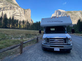 An RV rental parked in Yosemite Valley, showcasing towering rock formations & Half Dome. Ideal for a scenic nature trip.