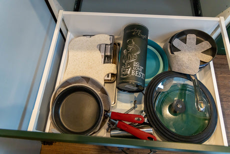 Compact RV rental drawer neatly stores kitchen essentials: pans with protectors, cutting board, and mixology barware.