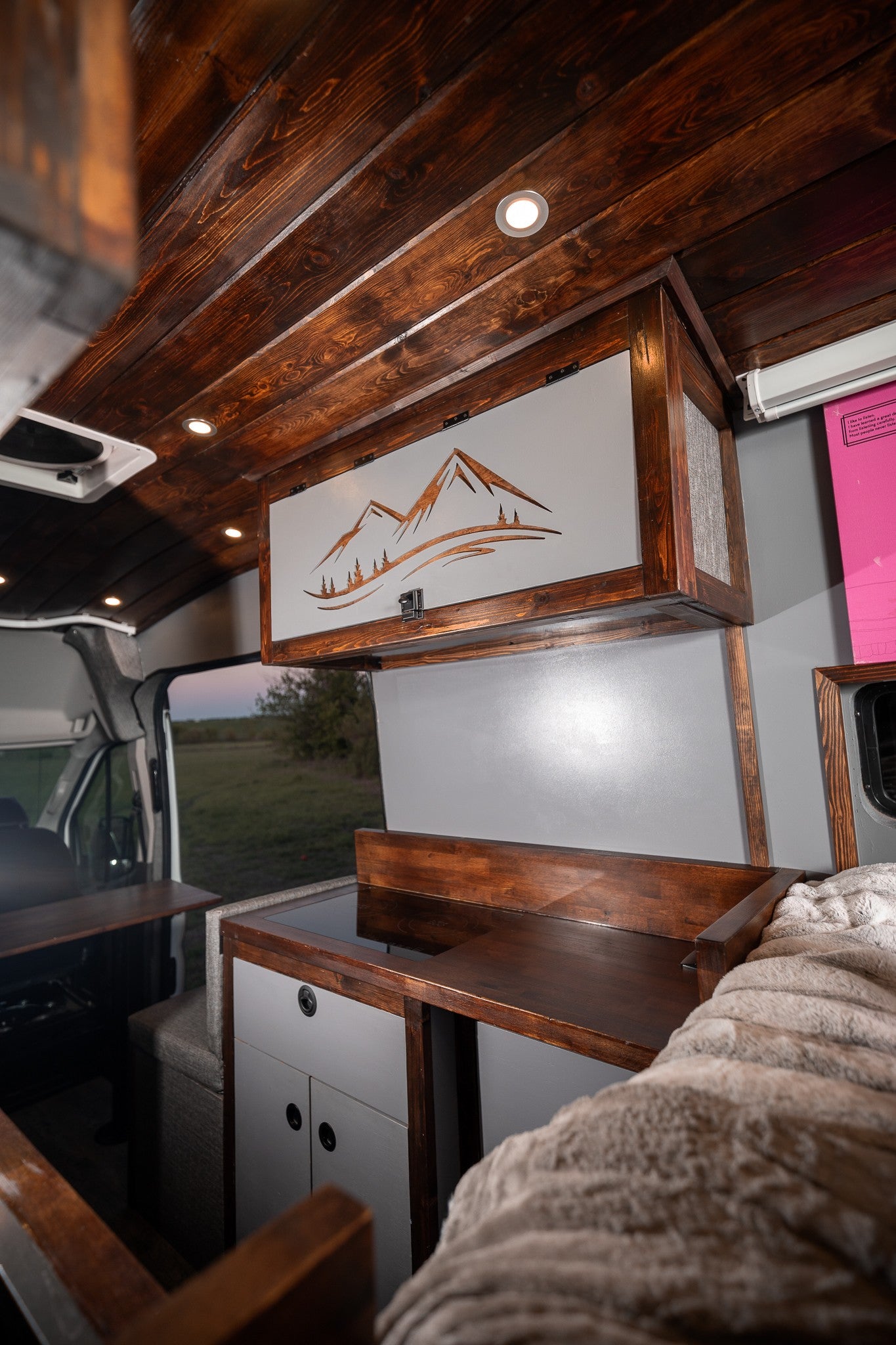 Cozy custom camper van interior, ready for your next adventure. Perfect for an rv rental, featuring wood and mountain art.