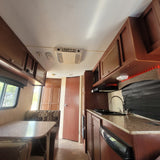 Step inside this RV rental showcasing a functional kitchen, cozy dinette, ample cabinets, and ceiling AC.