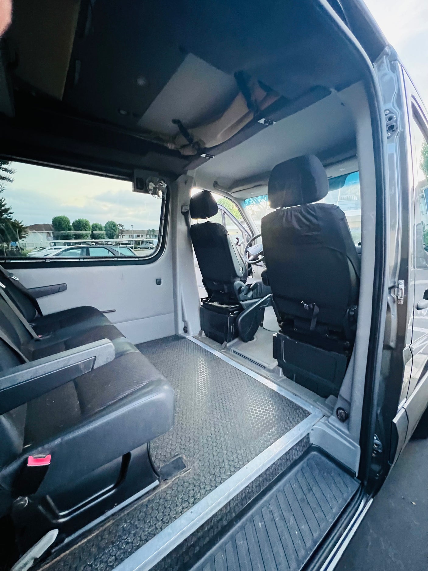 Spacious van interior, ideal for your next RV rental adventure. View from rear seats towards front, with open sliding door.