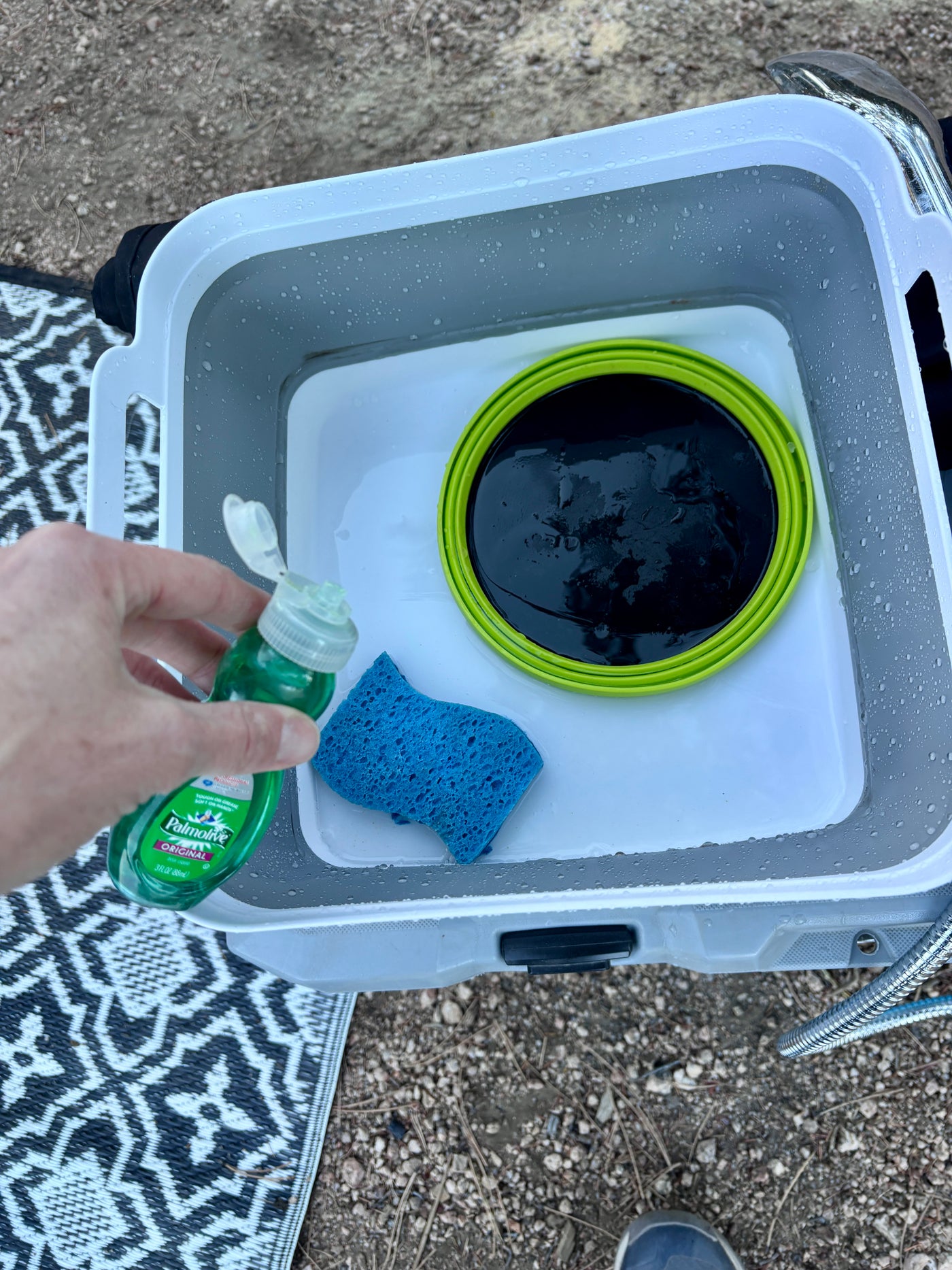 Camping dishwashing at an RV rental: Hand holding Palmolive soap over a sponge and dirty water in a wash tub. — photo 18