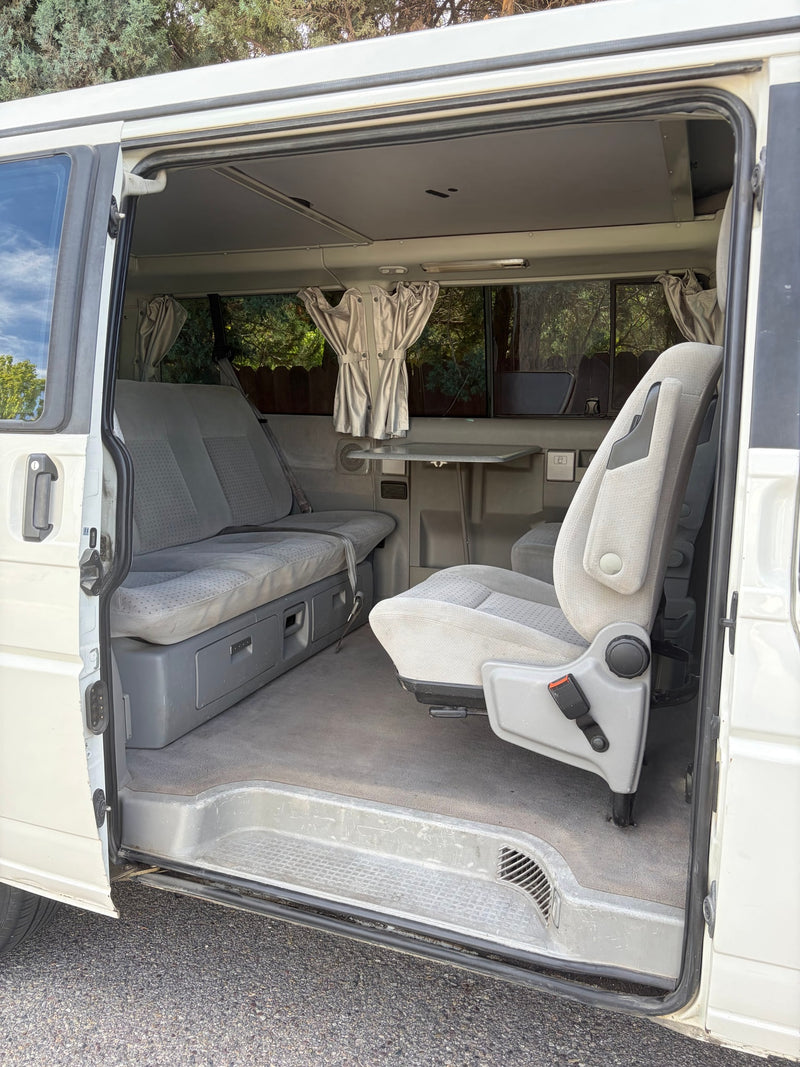 RV rental: Camper van interior showing swiveling passenger seat, rear bench, table, curtains & pop-top roof. — photo 8
