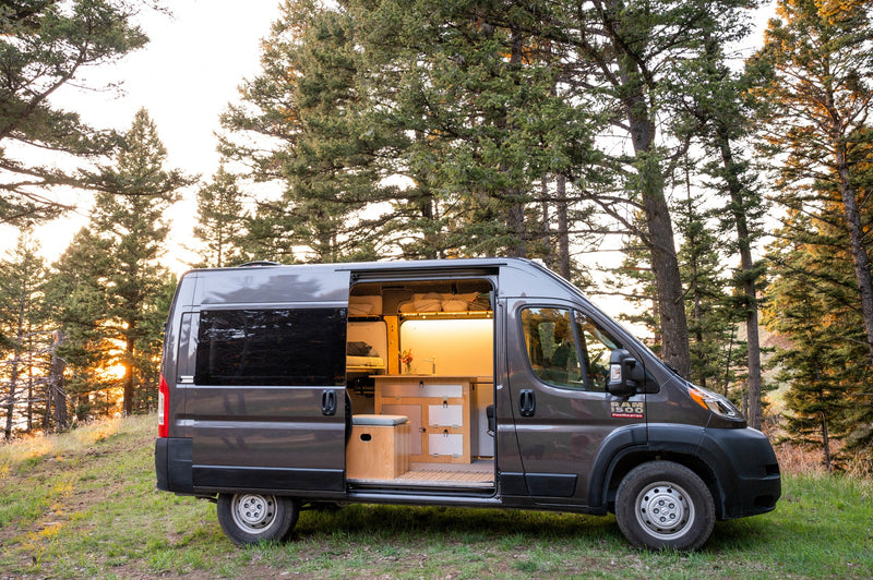 RV rental: a cozy gray camper van with an illuminated interior, parked in a pine forest, bathed in sunset glow. — photo 2
