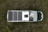 Overhead view of a gray RV rental with rooftop solar panels, parked in a grassy field, ready for off-grid travel.
