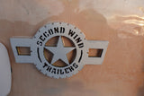 White & black 'Second Wind Trailers' logo with a star, set in clear resin on an RV panel, ready for rv rental.