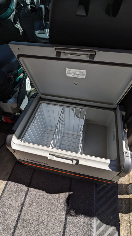 Inside an RV rental, a Dometic portable fridge is open, showing its empty compartments, ready for adventure.