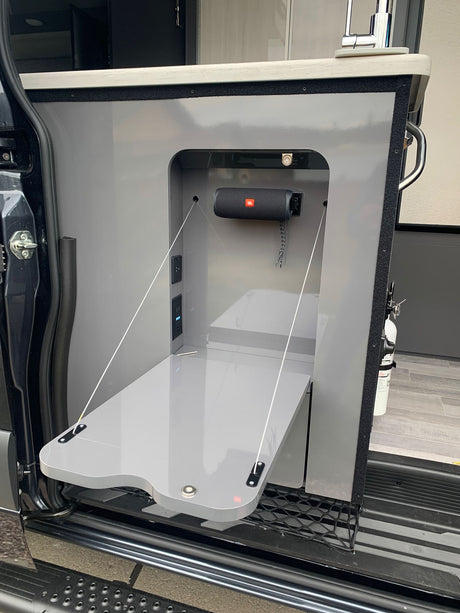 RV rental's clever side entry: fold-down table, JBL speaker, and power outlets for outdoor kitchen utility.