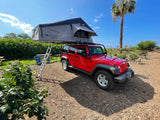 Red Jeep Wrangler with a Thule Tepui rooftop tent deployed, perfect for an RV rental adventure.
