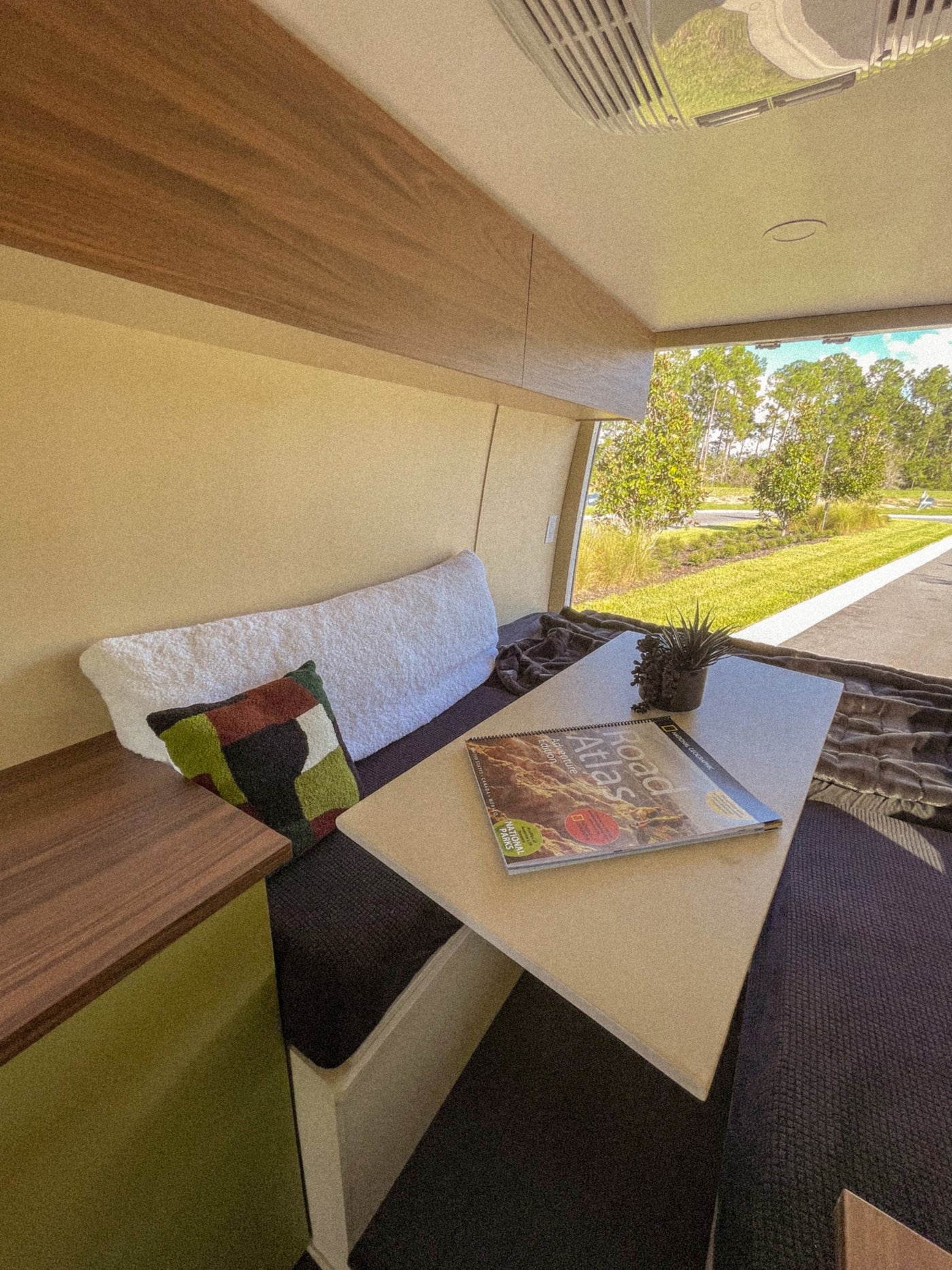 This RV rental offers a comfy bench, a table with a map, and a nature view, ideal for a relaxing travel experience. — photo 5