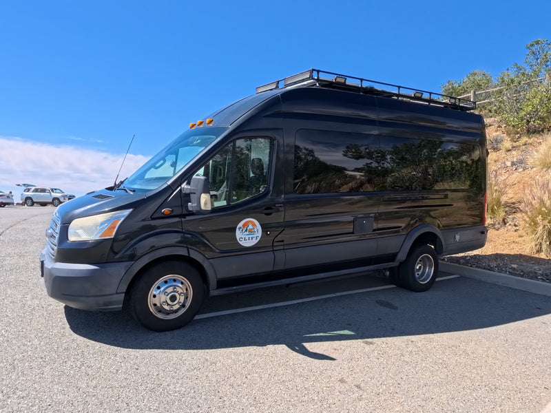 Black custom camper van RV rental from CLIFF. Equipped with a roof rack and lights — photo 1