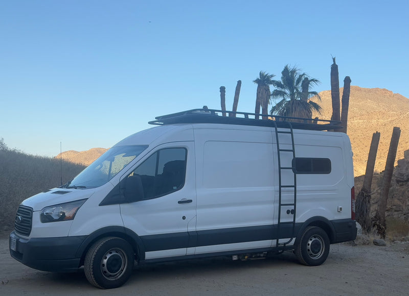 White camper van, an RV rental, with roof rack and ladder, parked in a desert with palms and arid mountains. — photo 12