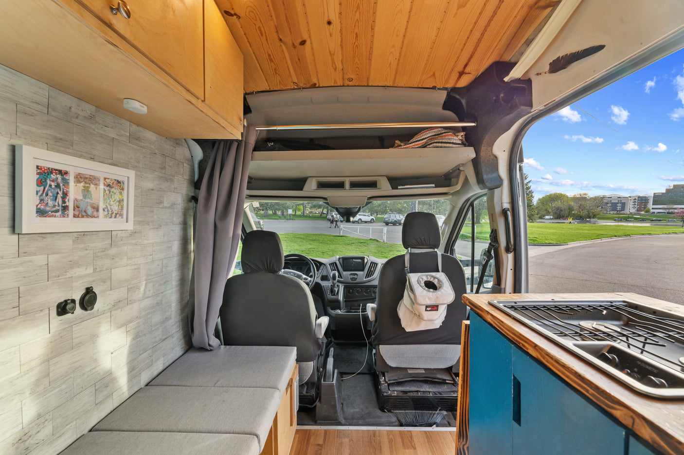 Inside a well-equipped camper van RV rental, featuring a cozy kitchen, seating area, and front cabin with a scenic view.