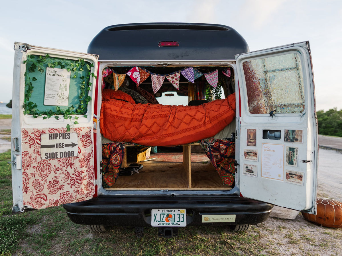  inviting adventure.|Friends enjoying their vibrant RV rental by the ocean. A perfect bohemian van life adventure.|Open back of an RV rental camper van revealing a vibrant bohemian interior with a cozy bed — photo 4