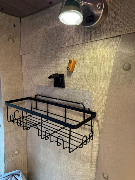 RV rental interior: wall-mounted storage basket, QC 3.0 USB charger, and overhead light for an organized space.