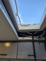 View from an RV rental: Bright blue sky through an open roof vent, with interior cabinets below. Great for travel.