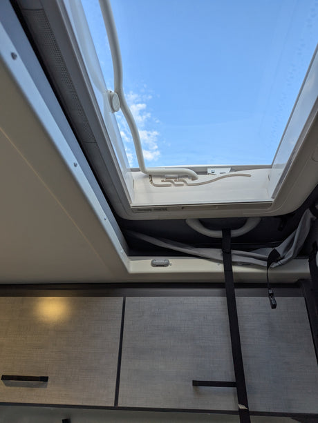 View from an RV rental: Bright blue sky through an open roof vent, with interior cabinets below. Great for travel.